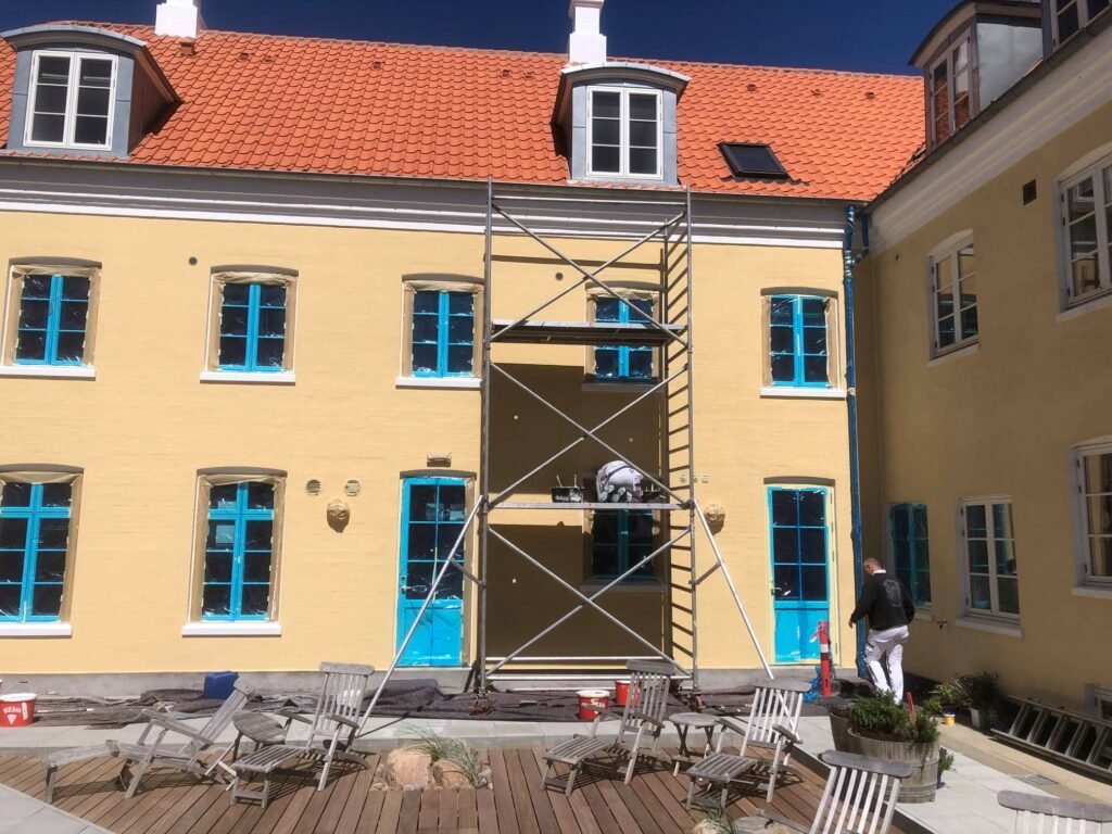 Bygning bliver renoveret med stillads og maling.
