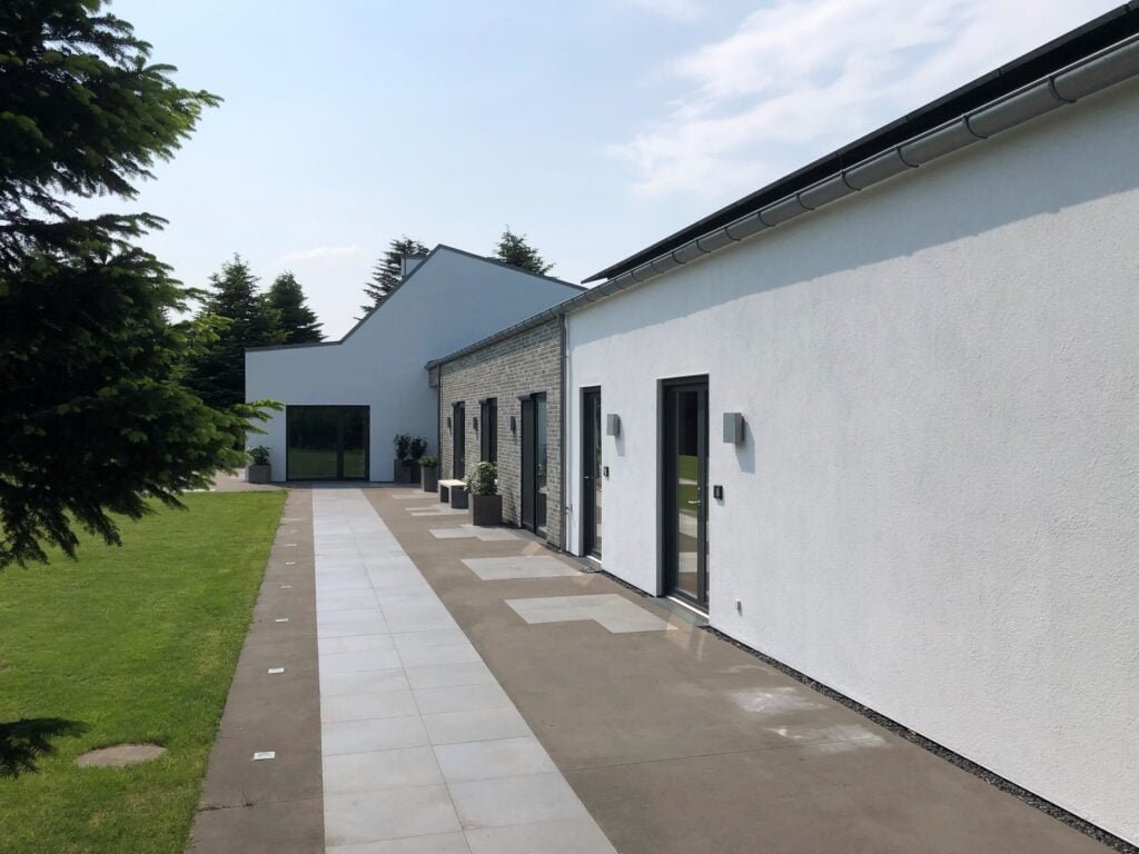 Moderne hus med terrasse og have på solskinsdag.