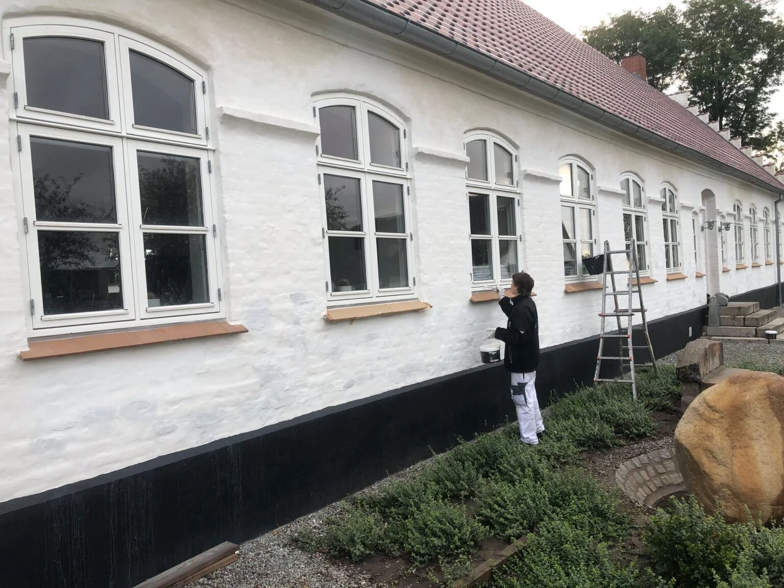 Maler arbejder på hvid bygning udendørs