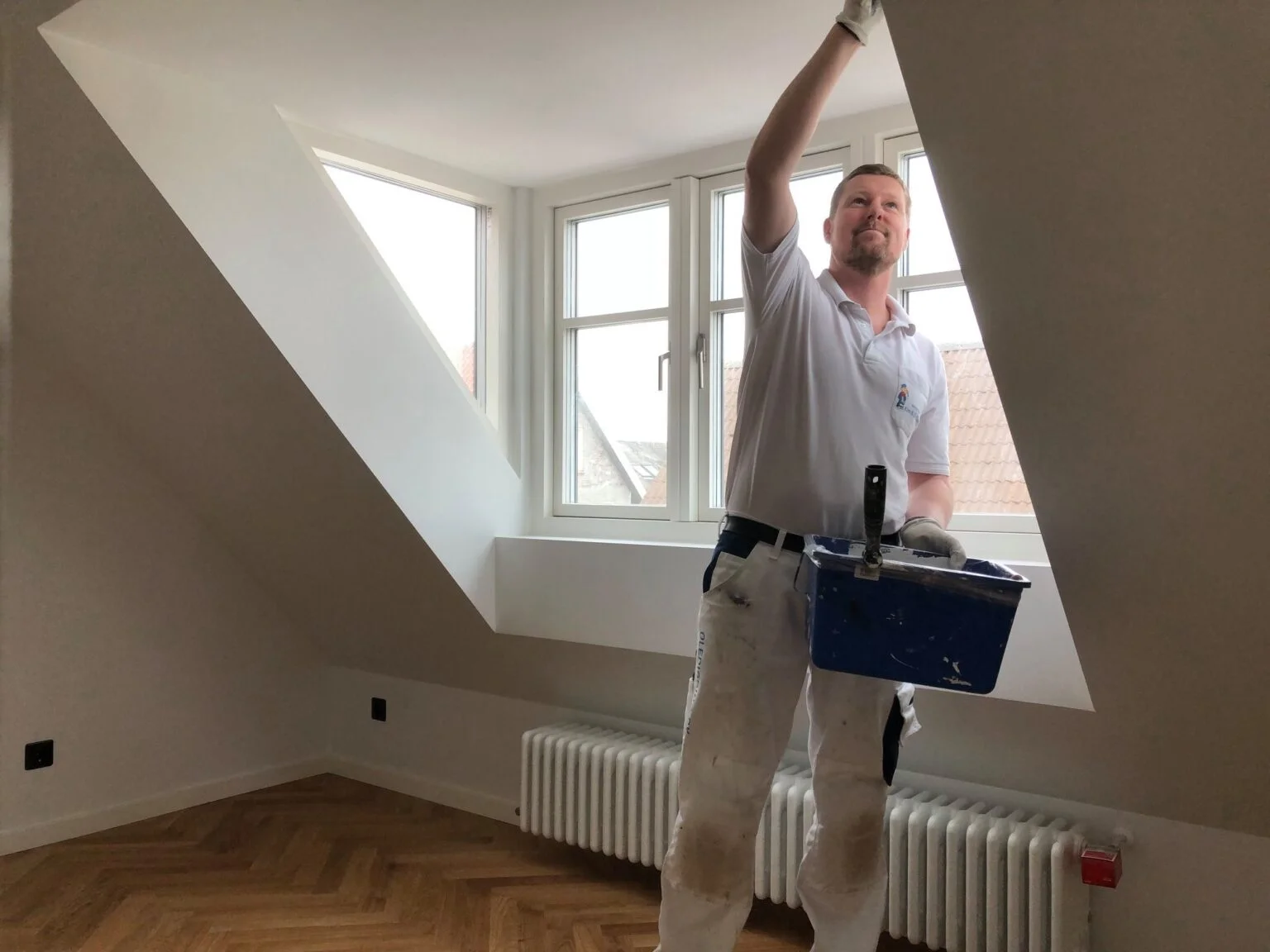 Maler arbejder i lys stue ved skråvæg